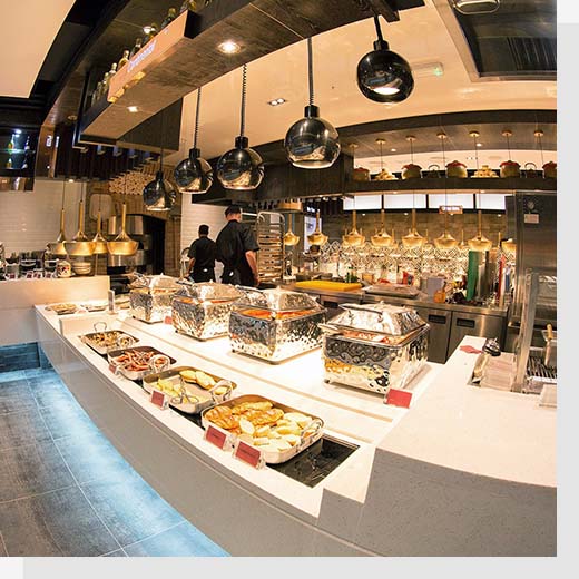 One of Cosmo's restaurants, showing food laid out in a buffet in the foreground with the kitchen in the background